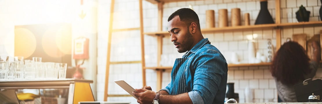Man stands in his business using an iPad