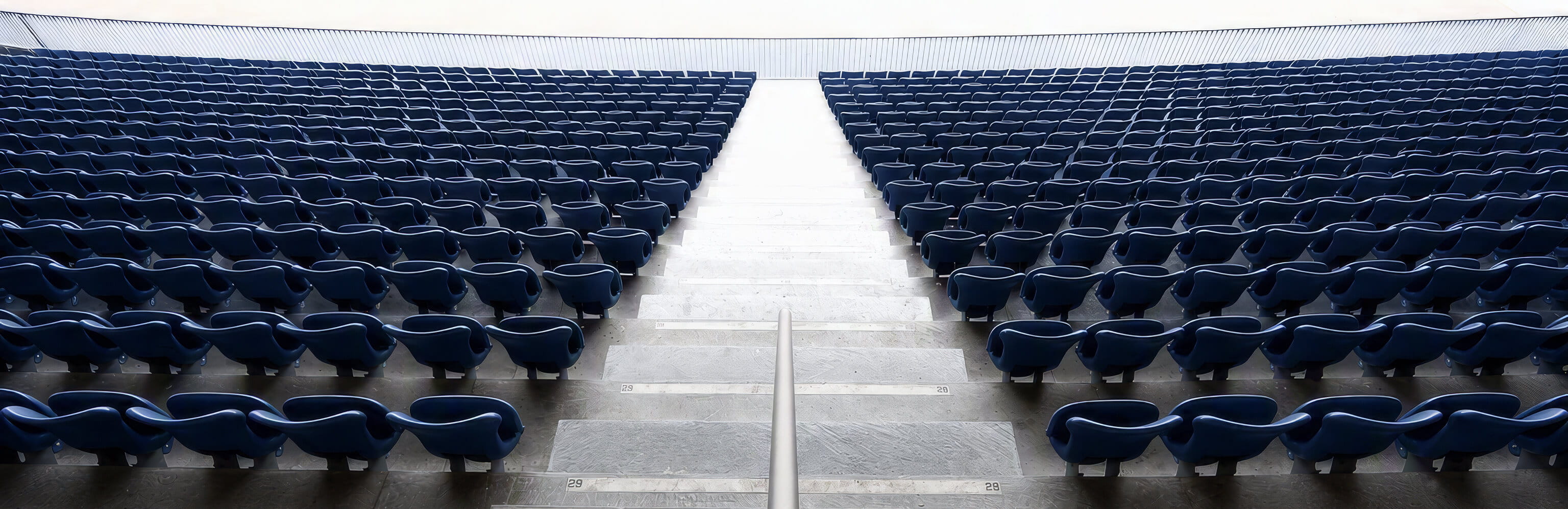 Empty stadium seating symbolizes the inverted wealth lifecycle of professional athletes, who often earn peak income early in life and must sustain it long after their playing careers end.